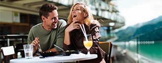 A Couple laughing while eating at an outdoor cafe.
