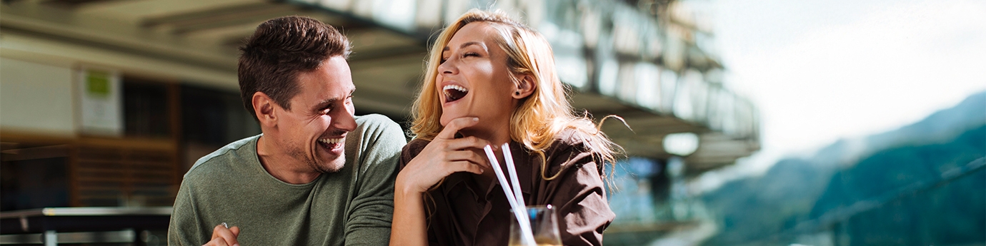 A Couple laughing while eating at an outdoor cafe.